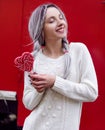 Closeup portrait amazing girl in the white warm woolen sweater with gray silver hair with red and white lollipop