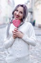 Closeup portrait amazing girl in the white warm woolen sweater with gray silver hair with red and white lollipop