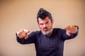 Closeup portrait of an angry adult man with a beard and iroquois poins with fingers at camera. People, emotions concept