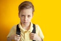 Closeup portrait angry child boy with backpack on yellow background. Back to school Royalty Free Stock Photo