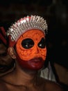 a closeup portrait of an artist with face paint makeup who performs theyyam