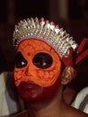 a closeup portrait of an artist with face paint makeup who performs theyyam