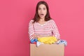 Closeup portrait of astonished female with widely opened mouth, lady with surprised facial expression holding box with clothes, Royalty Free Stock Photo