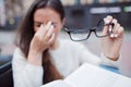 Closeup portrait of attractive female with eyeglasses in hand. Poor young girl has issues with vision. She rubs her nose and eyes Royalty Free Stock Photo