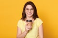 Closeup portrait of attractive pretty cheerful dark haired brunette girl in casual t-shirt and glasses, holding take away coffee, Royalty Free Stock Photo