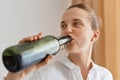 Closeup portrait of attractive woman with perfect skin wearing white shirt drinking of wine from bottle, female alcoholic enjoying Royalty Free Stock Photo