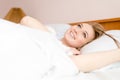 Closeup portrait of beautiful blonde young woman having fun happy smiling lying in white bed