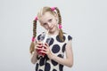 Closeup Portrait of Beautiful Caucasian Blond Girl With Pigtails Posing in Polka Dot Dress Against White.