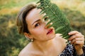 Closeup portrait of beautiful Caucasian middle age woman holding green leaf in summer park Royalty Free Stock Photo