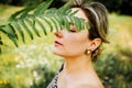 Closeup portrait of beautiful Caucasian middle age woman holding green leaf in summer park Royalty Free Stock Photo