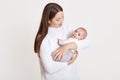 Closeup portrait of beautiful European woman holding on hands her little daughter on white background. Family, love, lifestyle,