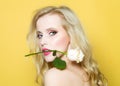 Closeup portrait of beautiful passionate woman in studio with bare shoulder and brigt makeup holding rose flower in