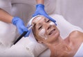 Closeup portrait of a beautiful senior Caucasian female applying face cream in a beauty salon Royalty Free Stock Photo