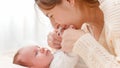 Closeup portrait of beautiful smiling mother kissing her baby& x27;s hands lying on bed against big window in bedroom Royalty Free Stock Photo