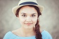 Closeup portrait of beautiful smiling white Caucasian brunette girl with brown eyes and plait, in blue dress and straw hat Royalty Free Stock Photo