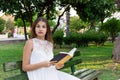 Closeup portrait of a beautiful surprised girl with wide opened eyes who is reading a book on the bench in the park. Human emotion Royalty Free Stock Photo