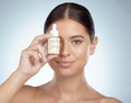 Closeup portrait beautiful woman holding face serum over eye while posing with copyspace. Young caucasian model isolated Royalty Free Stock Photo