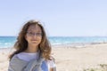 Closeup portrait of a beautiful young Caucasian fashion model posing on the seashore in sunny weather, looking in at us