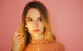 Closeup portrait. Beautiful young woman with a garland in her hand isolated on a pink background, looking aside with a serious Royalty Free Stock Photo