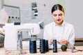 Closeup portrait of beautiful young woman seamstress sitting and sewing on sewing machine at her workshop. Dressmaker