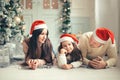 Family in Christmas Santa hats lying on bed. Mother father and baby having fun Royalty Free Stock Photo