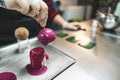 Closeup portrait of big praline being covered in pink icing by a professional pastry chef. Indoor shot. Copy space. Royalty Free Stock Photo