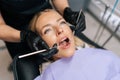 Closeup portrait of blonde female patient getting dental treatment in modern clinic, dentist doctor examining teeth of Royalty Free Stock Photo