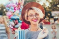 Closeup portrait of blonde girl with short haircut in amusement park on baloons background. She wears checkered dress Royalty Free Stock Photo