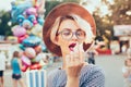 Closeup portrait of blonde girl with short haircut outdoor on baloons background. She wears checkered dress, hat Royalty Free Stock Photo