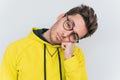 Closeup portrait of bored sleepy male in rounded glasses and wearing yellow hoodie posing against white wall. People, job,