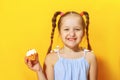 Closeup portrait of a cheerful little sweet tooth girl on a yellow background. The child smeared his nose with cream Royalty Free Stock Photo