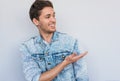 Closeup portrait of cheerful young smiling handsome male model wearing trendy jeans jacket, looking at aside and points away, Royalty Free Stock Photo