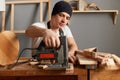 Closeup portrait of concentrated man carpenter working on woodworking machines in carpentry shop, sawing wood with an electric Royalty Free Stock Photo