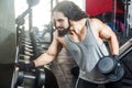 Closeup portrait of confident young adult man handsome athlete with long curly hair working out in gym, standing, holding one Royalty Free Stock Photo