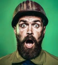 Closeup portrait of construction worker in safety hard hat. Amazed bearded architect builder in protective helmet