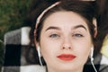 Close-up portrait of content young beautiful woman wearing headphones, listening to music with her eyes open and lying Royalty Free Stock Photo