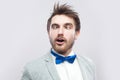 Closeup portrait of crazy funny handsome bearded man in casual grey suit and blue bow tie standing with crossed eyes and looking Royalty Free Stock Photo