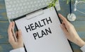 Closeup portrait of cropped health care professional with stethoscope and red tie, holding a sign which says health plan and Royalty Free Stock Photo