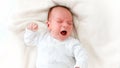 Closeup portrait of crying newborn baby lying in baby crib Royalty Free Stock Photo
