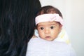 Closeup portrait of cute adorable awake Asian Chinese mixed race newborn baby girl with open eyes lying on parent shoulder