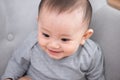 Closeup portrait of cute adorable smiling laughing, baby girl with black eyes sitting on sofa looking away from camera, natural Royalty Free Stock Photo