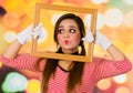Closeup portrait of cute curious young girl clown mime holding wooden frame looking to the side Royalty Free Stock Photo