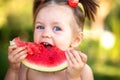 Closeup portrait of cute little girl eating watermelon on the grass in summertime Royalty Free Stock Photo