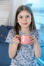 Closeup portrait of a cute little girl with a white milk mustache looking at the camera, pleased charming child with a Royalty Free Stock Photo