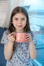 Closeup portrait of a cute little girl with a white milk mustache looking at the camera, pleased charming child with a Royalty Free Stock Photo