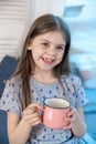 Closeup portrait of a cute little girl with a white milk mustache, pleased charming baby laughing. He holds a glass with Royalty Free Stock Photo