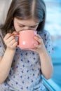 Closeup portrait of a cute little girl with a white milk mustache, pleased charming child with a smile holds a glass Royalty Free Stock Photo