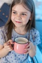 Closeup portrait of a cute little girl with a white milk mustache, pleased charming child with a smile holds a glass Royalty Free Stock Photo