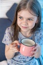 Closeup portrait of a cute little girl with a white milk mustache, pleased charming child with a smile holds a glass Royalty Free Stock Photo