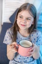 Closeup portrait of a cute little girl with a white milk mustache, pleased charming child with a smile holds a glass Royalty Free Stock Photo